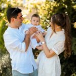 A joyful young family spending quality time together in a sunny outdoor park setting.